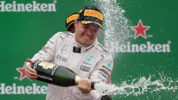 Pembalap Mercedes Nico Rosberg dari Jerman merayakan kemenangannya dengan membuka botol sampanye di podium setelah balapan F1 Grand Prix Italia, di Monza, Italia Minggu (04/9). Balapan ini merupakan kemenangan ketujuh di musim ini. (Reuters/Max Rossi)
