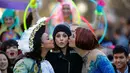 Aktris Mila Kunis (tengah) dicium oleh Amira Weeks (kiri) dan Jacques Berguig dalam sebuah parade di Cambridge (25/1). Mila Kunis dinobatkan sebagai "Woman of the Year" oleh kelompok teater Hasty Pudding. (AP Photo / Charles Krupa)