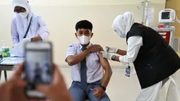 Seorang siswa SMA menerima dosis vaksin virus corona COVID-19 Pfizer di Rumah Sakit Zainoel Abidin, Banda Aceh, Aceh, Selasa (9/11/2021). Vaksinasi COVID-19 di kalangan warga Kota Banda Aceh tembus 80 persen. (CHAIDEER MAHYUDDIN/AFP)