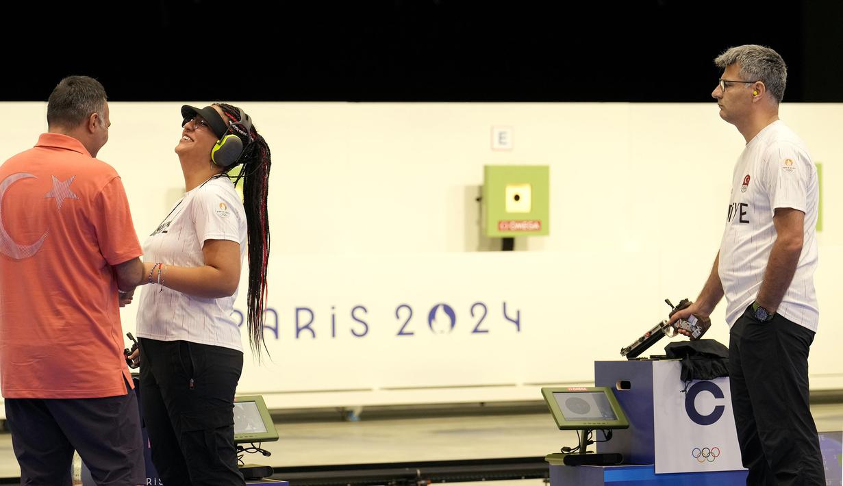 Penembak Turki, Yusuf Dikec (kanan) dan Sevval Ilayda Tarhan memperhatikan instruksi pelatih saat bertanding dalam perebutan medali emas cabang olahraga menembak nomor 10m Air Pistol beregu campuran Olimpiade Paris 2024 di Chateauroux Shooting Centre, Paris, Prancis, Rabu (30/07/2024). (AP Photo/Manish Swarup)