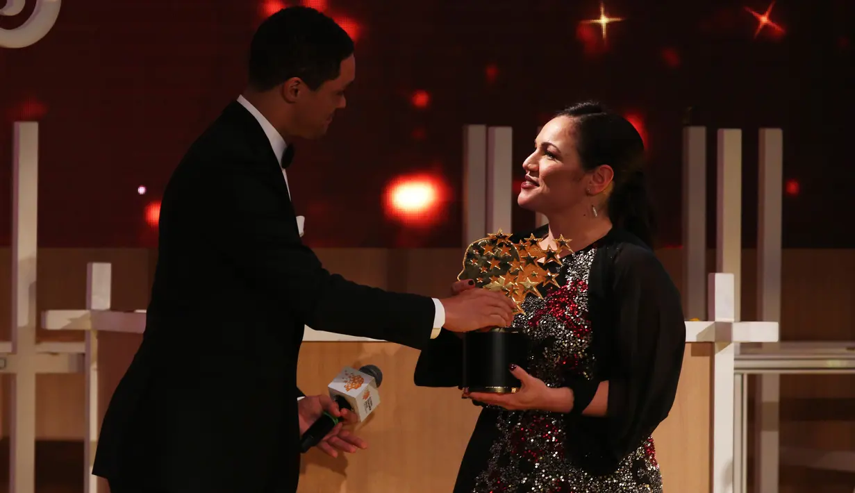 Guru sekolah Inggris, Andria Zafirakou menerima trofi Global Teacher Prize dari komedian Trevor Noah pada acara penganugerahan di Dubai, Minggu (18/3). Untuk itu Andria Zafirakou mendapatkan uang US $ 1 juta atau hampir Rp 14 miliar. (AP/Jon Gambrell)