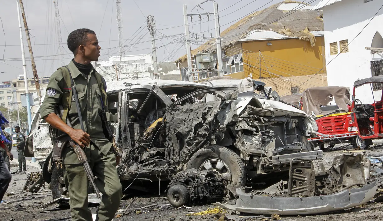 Seorang anggota pasukan keamanan berjalan melewati reruntuhan di lokasi pemboman di Mogadishu, Somalia (13/2/2021). Bom mobil meledak di Mogadishu, Somalia di luar kompleks parlemen dan tak jauh dari Istana Kepresidenan Somalia. (AP Photo/Farah Abdi Warsameh)