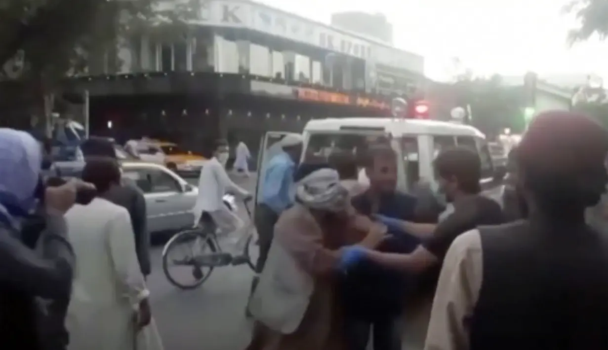 Orang-orang merawat orang yang terluka di dekat lokasi ledakan mematikan di luar bandara di Kabul, Afghanistan, Kamis (26/8/2021). Korban tewas kini bertambah menjadi 20 orang. (Aśvaka News Agency via AP)