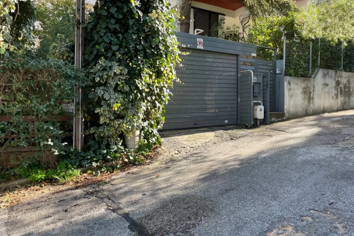 Pintu garasi rumah seorang diplomat senior Italia di pinggiran kota Athena, Yunani ditutup menyusul serangan yang menghancurkan sebuah mobil dan merusak yang kedua. (Lefteris Pitarakis/AP)