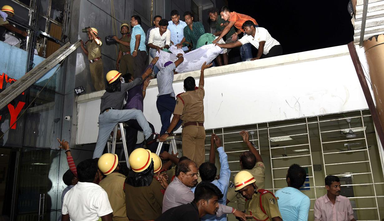 Petugas penyelamat menurunkan tubuh salah satu korban kebakaran besar yang melanda rumah sakit SUM Bhubaneshwar di Odisha, India Timur, Senin (17/10). Api diduga muncul karena hubungan arus pendek, namun dugaan itu masih diselidiki pihak berwenang. (AFP)