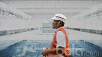 Pekerja melintas di depan gambar ilustrasi kolam renang di Komplek SUGBK. Kolam renang tersebut akan diubah menjadi aquatic center modern dengan kolam renang dalam ruangan. (Bola.com/M Iqbal Ichsan)
