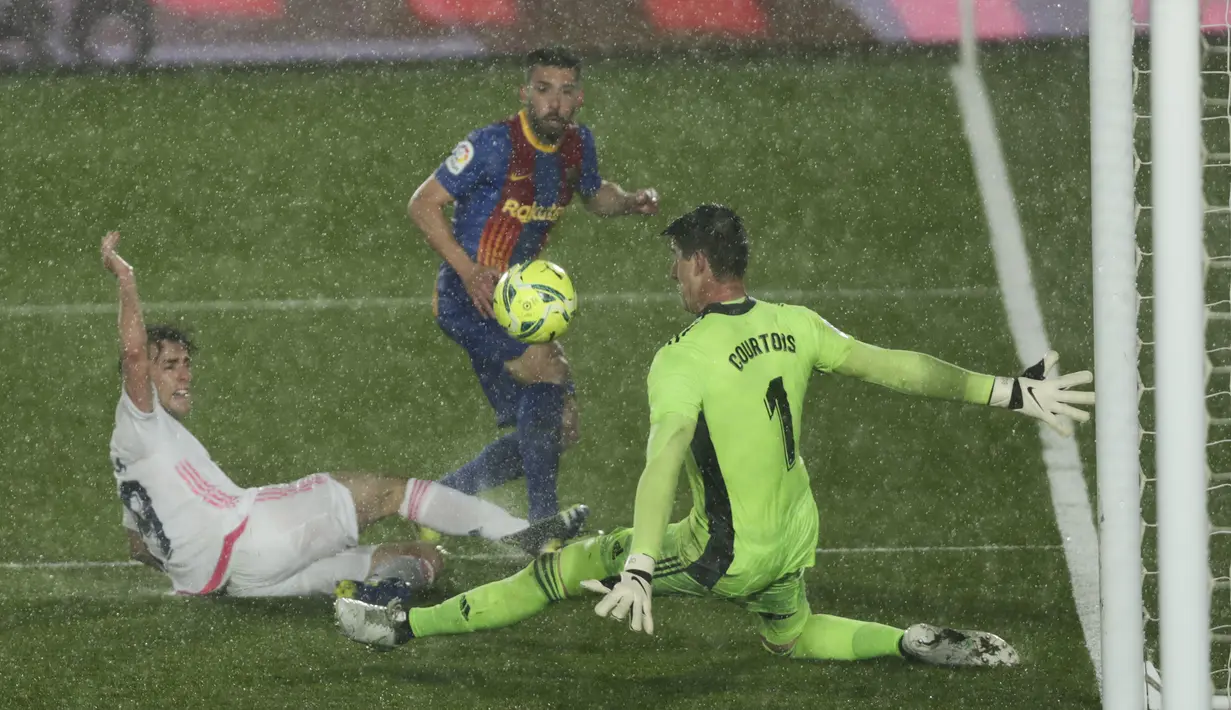 Bek Barcelona, Jordi Alba berebut bola dengan kiper Real Madrid Thibaut Courtois (kanan) dan Alvaro Odriozola pada pekan ke-30 Liga Spanyol di Estadio Alfredo Di Stefano, Minggu dinihari WIB (11/4/2021). Real Madrid kembali sukses taklukkan rival abadinya Barcelona 2-1. (AP Photo/Manu Fernandez)