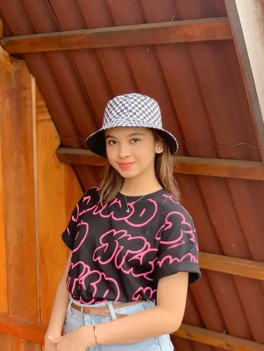 Kali ini, Lyodra tampil dengan gaya casual dengan memadukan t-shirt warna hitam-pink dengan celana jeans. Aksesori topi fedora motif plaid pun membuat looknya makin kece. (Instagram/lyodraofficial).