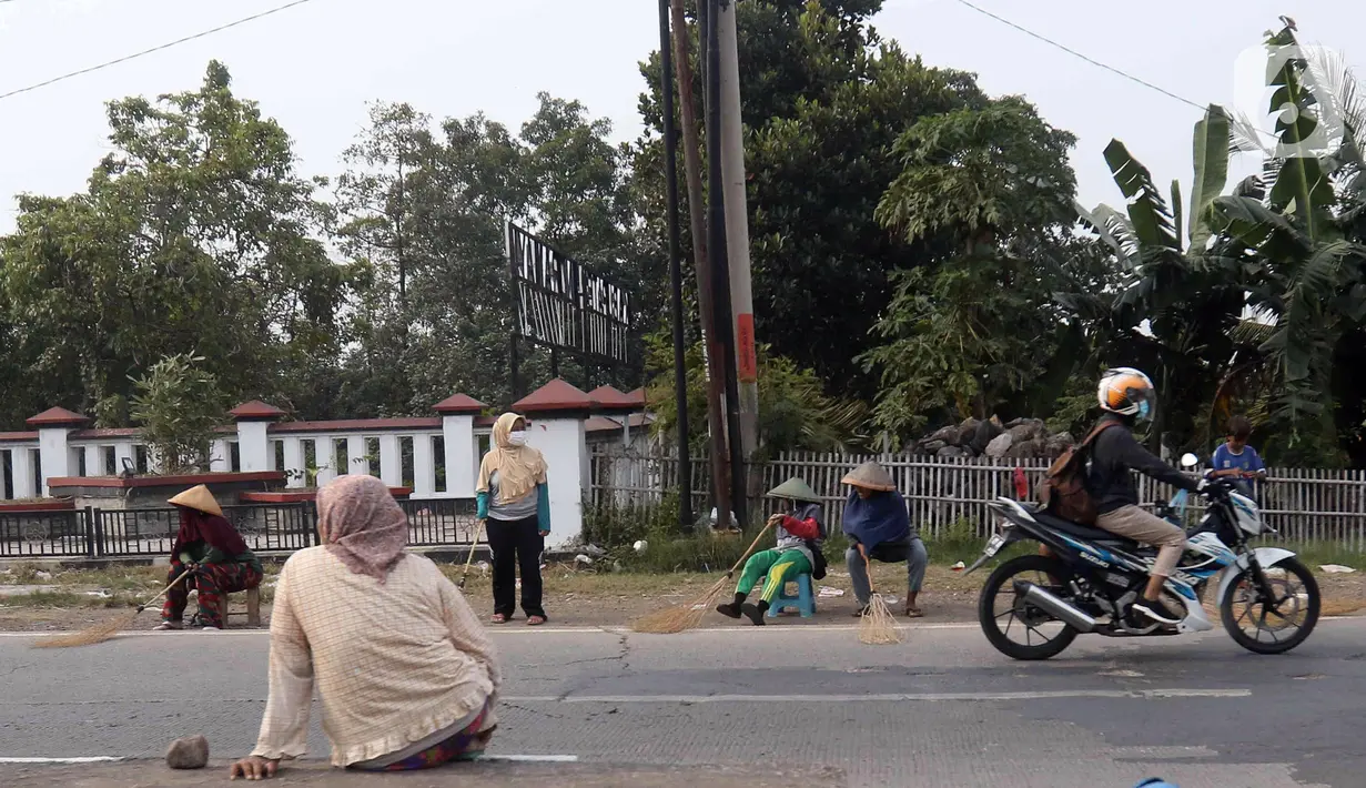 <p>Sejumlah warga menunggu pengendara kendaraan bermotor memberi sedekah dengan melempar uang di kawasan Jembatan Sewo, Indramayu, Jawa Barat, Jumat (29/4/2022). Aksi mengambil uang sedekah menggunakan sapu meningkat saat puncak arus mudik. (Liputan6.com/Herman Zakharia)</p>