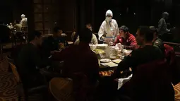 Seorang pramusaji dengan pakaian pelindung diri atau hazmat menyajikan meja di sebuah restoran di dalam Hotel Shangri-La pada Olimpiade Musim Dingin 2022, 16 Februari 2022, di Beijing. (AP Photo/Jae C.Hong)