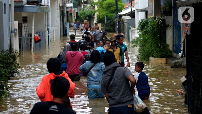 Warga melewati banjir yang menggenangi kawasan Kampung Pulo, Jakarta, Kamis (2/1/2020). Hujan yang terjadi kemarin malam membuat Kali Ciliwung meluap ke jalan. (merdeka.com/Imam Buhori)
