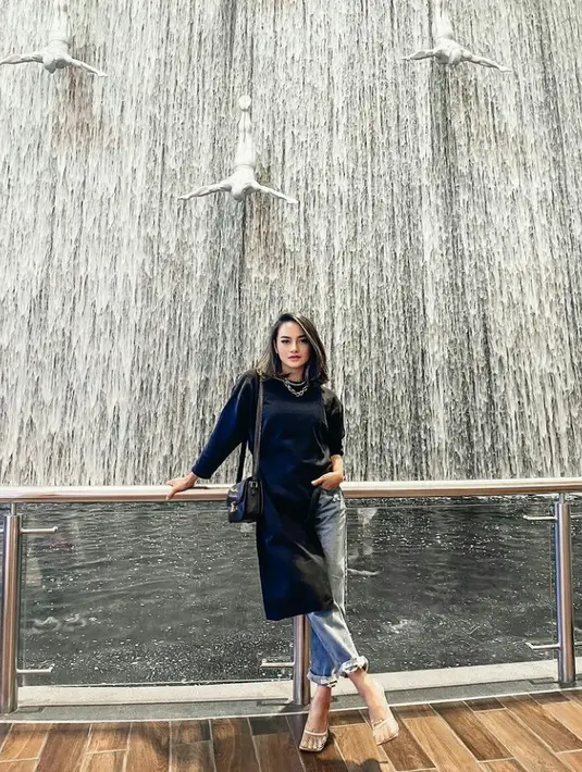 Tampil modis dengan kombinasi baju rajut asimetris warna hitam, celana jeans, dan sling bag. Sebagai pemanis tambahkan necklace chain warna silver. (Foto:Instagram/ririnekawati).