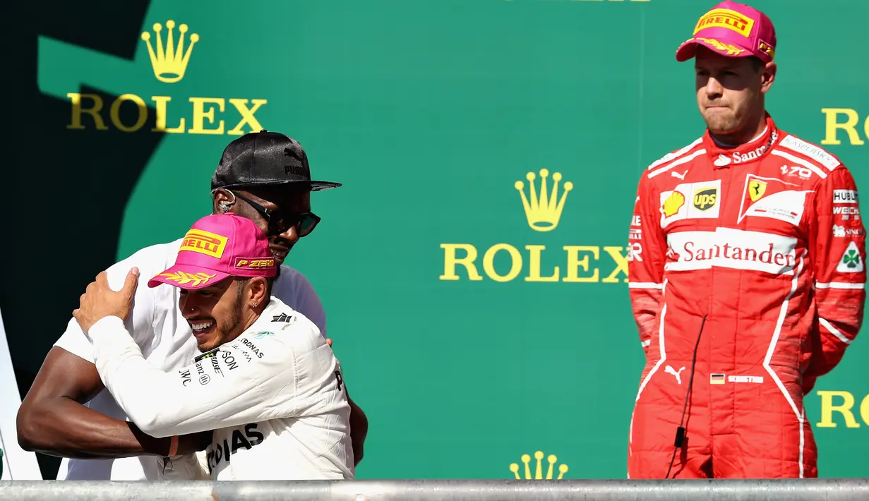 Pembalap Marcedes, Lewis Hamilton memeluk mantan atlet lari cepat asal Jamaika, Usain Bolt saat mendapat ucapan selamat di atas podium GP Amerika Serikat di Circuit of Americas, Minggu (22/10). (MARK THOMPSON / GETTY IMAGES / AFP)