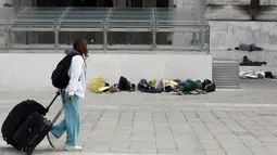 Seorang wanita berjalan di dekat sejumlah imigran yang tidur di luar stasiun kereta api Milan, Jumat (12/6/2015). (REUTERS/Stefano Rellandini)