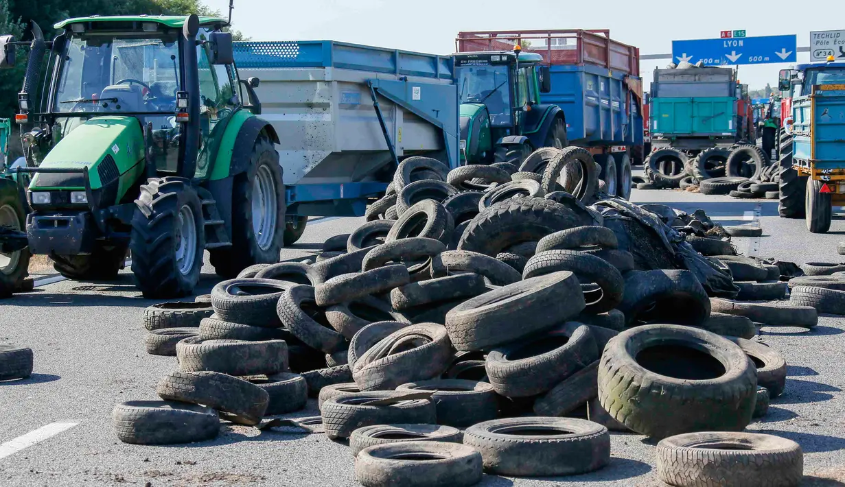 Petani Perancis memblokir jalan raya A6 dengan traktor dan ban di Limonest, dekat Lyon, Prancis (23/7/2015). Petani Perancis memprotes kembali ketidak seimbangan keuntungan yang diperoleh antara petani dan pengecer. (REUTERS/Robert Pratta)