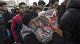 Seorang wanita menggendong anaknya saat mengantre untuk menaiki kereta di stasiun kereta api Beijing, Tiongkok (10/2). Jutaan orang yang berada di Beijing meninggalkan kota tersebut untuk pulang ke kampung jelang perayaan Imlek. (AFP Photo/Fred Dufour)