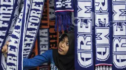 Seorang Aremanita melihat-lihat syal Arema FC yang dijual oleh pedagang kaki lima jelang laga semifinal Piala Presiden 2017 antara Arema FC melawan Semen Padang di sekitar Stadion Kanjuruhan, Malang, Jawa Timur, Minggu (5/3/2017). (Bola.com/Vitalis Yogi T