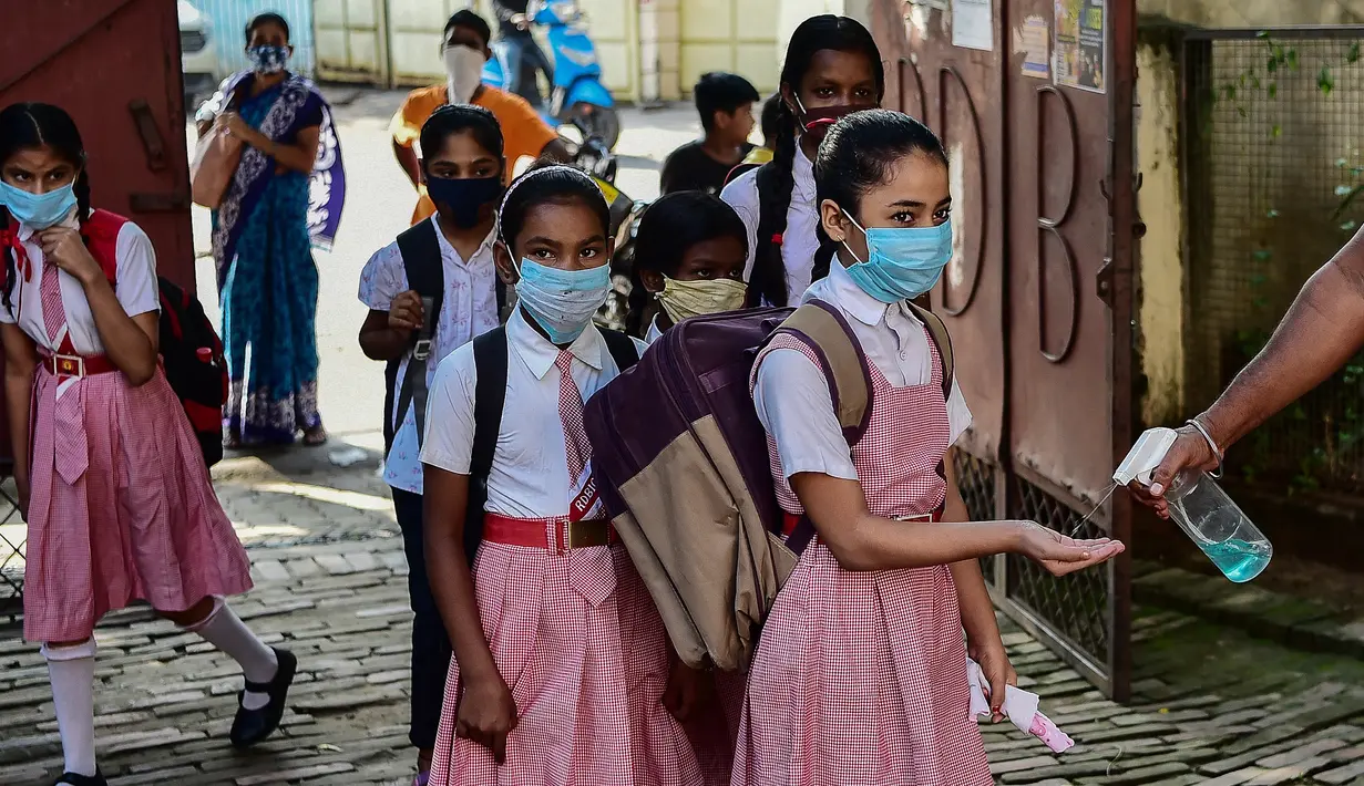 Staf membantu siswa dengan pembersih tangan saat mereka tiba di sebuah sekolah di Allahabad, India, Rabu (1/9/2021). Pemerintah negara bagian melonggarkan lockdown COVID-19 untuk lembaga pendidikan yang memungkinkan siswa menghadiri sekolah tatap muka dengan 50 persen kapasitas. (SANJAY KANOJIA/AFP)