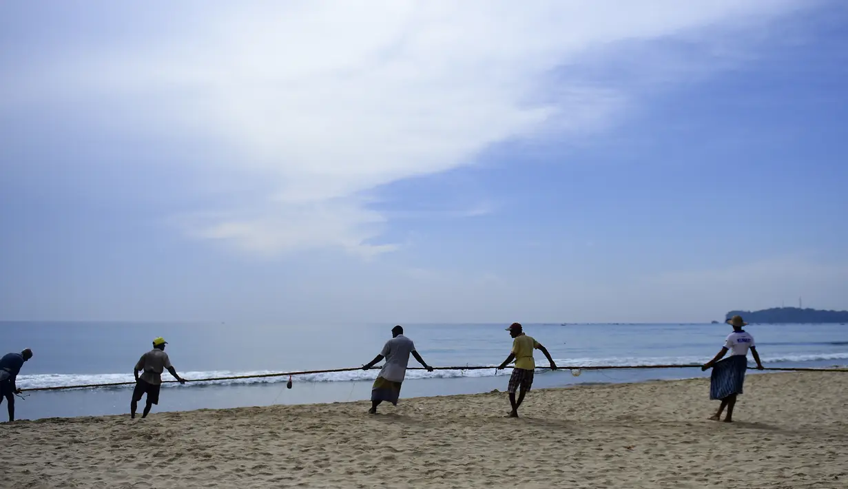 Para nelayan Sri Lanka menarik jaring ikan di pantai di Trincomalee (5/5). Trincomalee adalah kota pelabuhan di bagian timur Sri Lanka. (AFP Photo/Ishara S Kodikara)