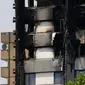 Kondisi bangunan apartemen Grenfell Tower di London usai kebakaran dahsyat, Minggu (18/6). Perkembangan terakhir menyebutkan 30 orang tewas dan lebih dari 70 residen masih hilang dalam insiden kebakaran apartemen 24 lantai itu. (TOLGA AKMEN/AFP)