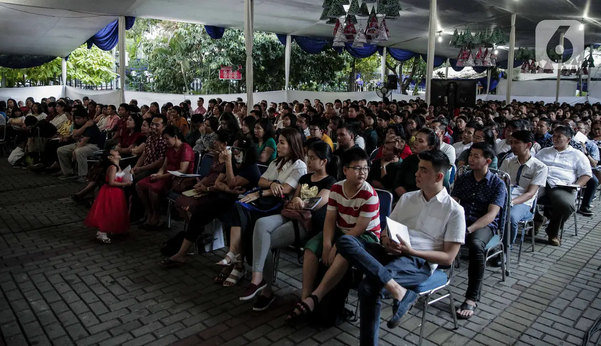 Jemaat melaksanakan misa malam Natal di bagian luar Gereja Katedral, Jakarta, Selasa (24/12/2019). Jemaat memenuhi area dalam dan luar gereja. (Liputan6.com/Faizal Fanani)
