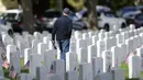 Seorang pria membawa karangan bunga melewati deretan batu nisan di Pemakaman Nasional Fort Logan, Sheridan, Colorado, Amerika Serikat, 30 Mei 2022. (AP Photo/David Zalubowski)