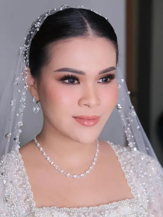 Sang MUA tampak mengaplikasikan eyeshadow coklat dan bulu mata yang dramatis untuk riasan matanya. Di pipinya, diaplikasikan blush on warna coral. Begitu pun di bibirnya yang diaplikasikan lipstik satin warna coral senada dengan warna pipinya.  [IG/malvava]