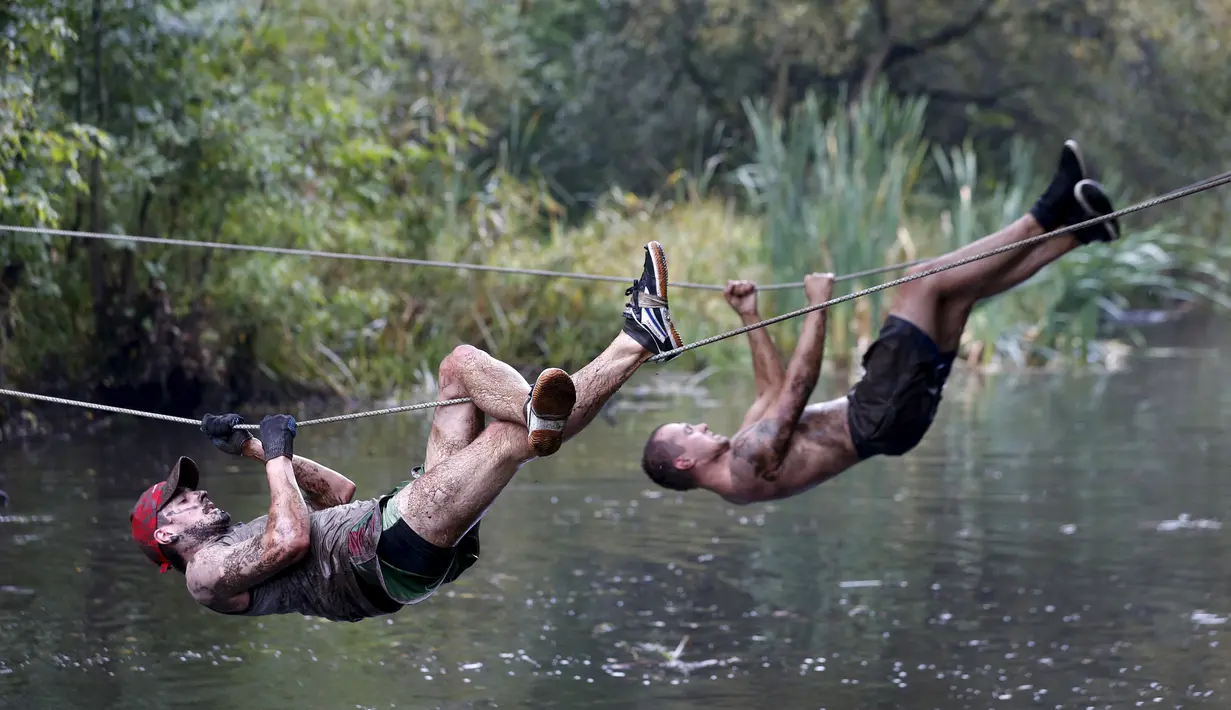 Peserta menyebrangi sungai dengan sebuah tali saat mengikuti kompetisi lari ekstrim di Zhodino, Minsk timur, Belarus, 26 September 2015. (REUTERS/Vasily Fedosenko)