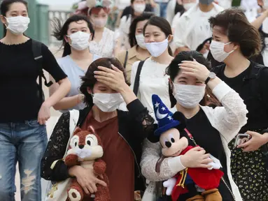 Pengunjung mengenakan masker guna melindungi diri dari virus corona berjalan menuju pintu masuk Tokyo Disneyland di Urayasu, dekat Tokyo, Rabu (1/7/2020). Tokyo Disneyland dibuka kembali untuk pertama kalinya dalam empat bulan setelah menangguhkan operasi karena kekhawatiran Covid-19. (AP/Koji Sasah
