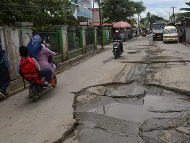 Warga melewati jalan yang rusak parah di Jalan Raya Tanjung Pasir, Tangerang, Banten, Rabu (22/1/2025). (merdeka.com/Arie Basuki)