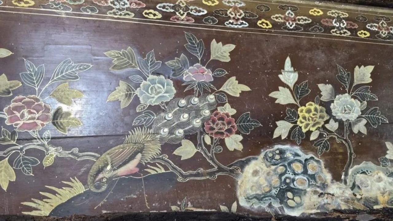 Bunga berwarna cerah, rerumputan, dan khususnya burung merak dilukis di peti bagian dalam yang terawat baik.