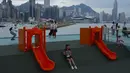 Orang-orang berjalan di taman tepi laut melawan Pelabuhan Victoria saat Badai Tropis Kompasu mendekati Hong Kong, Selasa (12/10/2021). Observatorium Hong Kong mengeluarkan sinyal nomor 8, level tertinggi ketiga dalam skalanya, saat siklon tropis Kompasu semakin mendekati kota. (AP Photo/Vincent Yu)