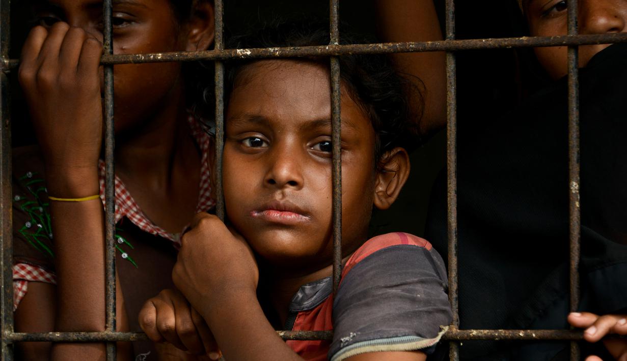 Anak-anak pengungsi Rohingya menunggu di pusat penampungan sementara bekas kantor Imigrasi Punteuet di Lhokseumawe, Aceh Utara (26/6/2020). Hampir 100 pencari suaka Rohingya yang terdampar di lepas pantai Aceh pada (25/6/2020) lalu. (AFP Photo/CHAIDEER MAHYUDDIN)