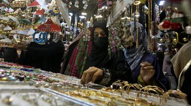 Gadis-gadis muda melihat-lihat perhiasan buatan tradisional saat dia dan yang lainnya mengunjungi pasar untuk berbelanja perayaan Idul Fitri mendatang, di Karachi, Pakistan, Jumat, 29 April 2022. Idul Fitri menandai akhir bulan suci Ramadhan. (AP Photo/Fareed Khan)