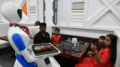 Sebuah robot mengantarkan pesanan makanan kepada pelanggan saat pembukaan restoran di Bangalore, India, Sabtu (17/8/2019). Restoran tersebut memperkenalkan satu robot pengantar serta lima robot untuk berinteraksi dan menyajikan makanan bagi para pelanggannya. (Manjunath Kiran/AFP)