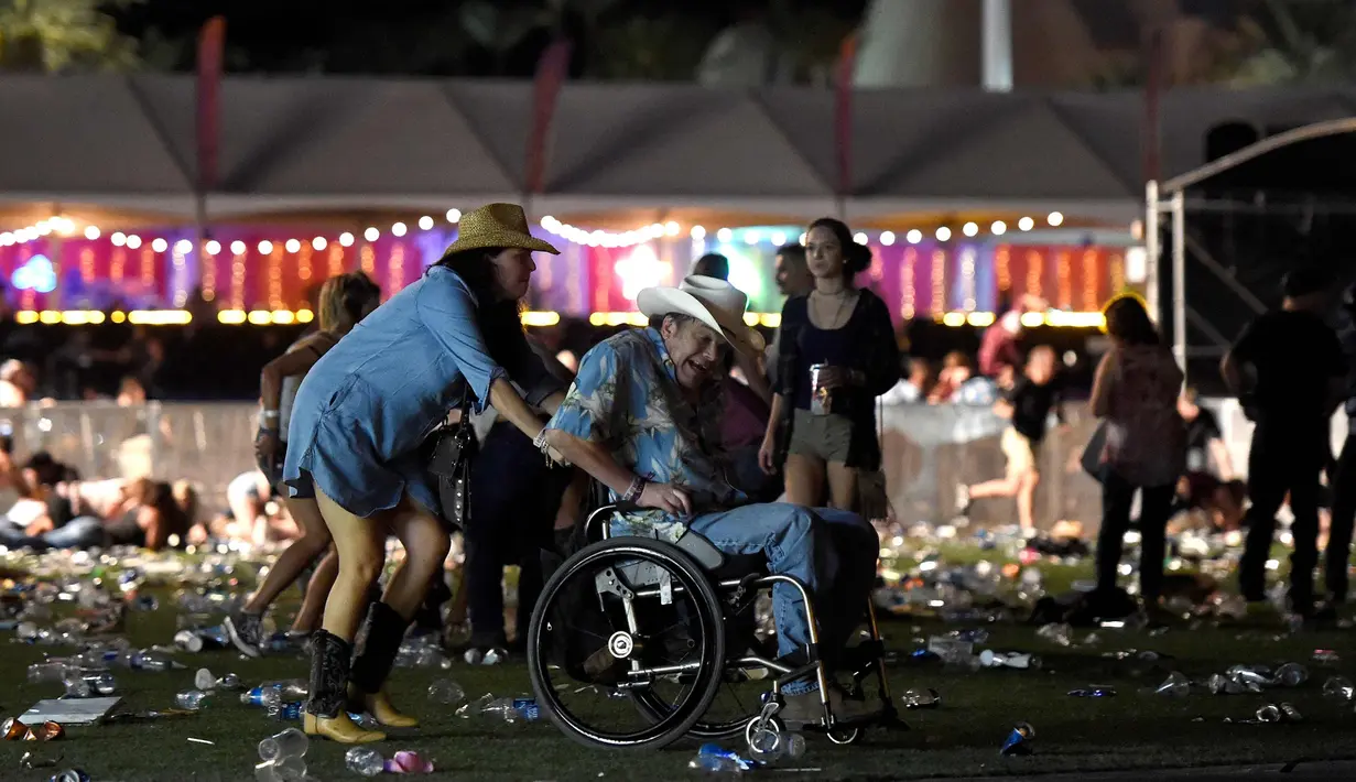 Pengunjung mengenakan kursi roda menghindar saat terjadi penembakan di Las Vegas, Nevada (1/10). Pelaku penembakan disebut menembak seorang petugas keamanan dan polisi setempat. (David Becker/Getty Images/AFP)