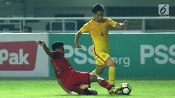 Bek Timnas Indonesia U-19, Asnawi Mangkualam (kiri) berusaha menahan pemain China U-19, Junwei Yu pada laga PSSI 88th U-19 International Tournament di Stadion Pakansari, Cibinong, Selasa (25/9). Indonesia kalah 0-3. (Liputan6.com/Helmi Fithriansyah)