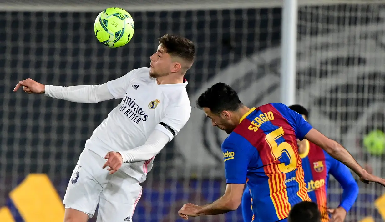 Gelandang Real Madrid, Federico Valverde (kiri) berduel udara dengan gelandang Barcelona, Sergio Busquets dalam laga lanjutan Liga Spanyol 2020/2021 pekan ke-30 di Alfredo di Stefano Stadium, Madrid, Sabtu (10/4/2021). Real Madrid menang 2-1 atas Barcelona. (AFP/Javier Soriano)