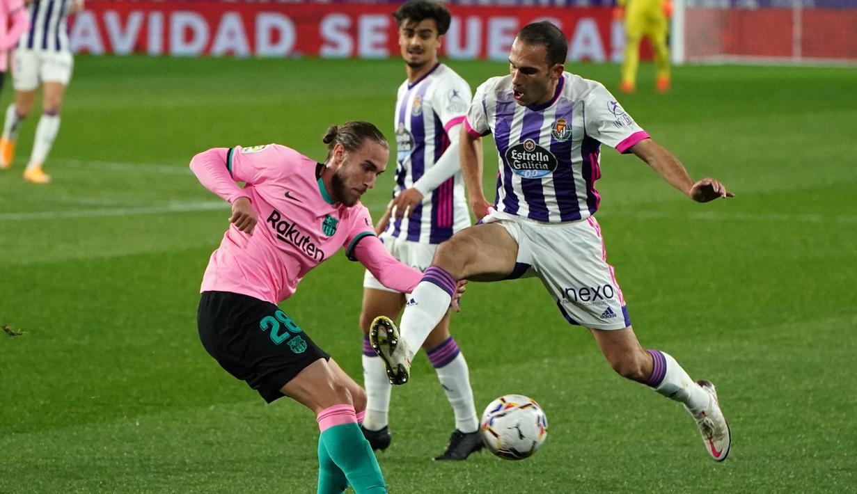 Bek Barcelona, Oscar Mingueza, berebut bola dengan bek Valladolid, Nacho Martinez, pada laga lanjutan Liga Spanyol di Jose Zorrilla Stadium, Rabu (23/12/2020) dini hari WIB. Barcelona menang 3-0 atas Valladolid. (AFP/Cesar Manso)