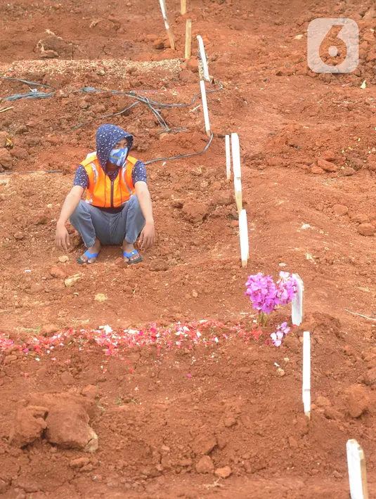 Seorang pria pelanggar PSBB berdoa di makam korban Covid-19 di TPU Jombang, Tangerang Selatan, Senin (18/1/2020). Petugas Satpol PP bersama Polres Tangsel memberikan hukuman bagi 17 pelanggar PSBB yang terkena razia masker di kawasan Bintaro. (merdeka.com/Arie Basuki)