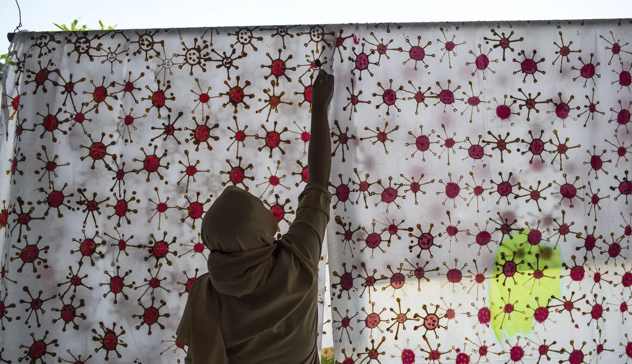 Penyandang disabilitas menjemur kain batik dengan motif virus corona di Surabaya, Jawa Timur (19/8/2020). Di tengah pandemi Covid-19, sekelompok penyandang disabilitas di Surabaya membuat batik bermotifkan virus corona. (AFP/JUNI KRISWANTO)