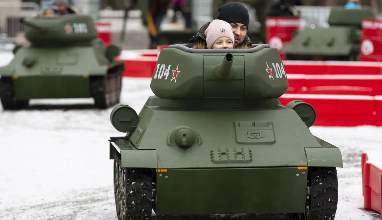 Seorang anak ditemani seorang pria mengendarai model tank T-34 era Soviet yang legendaris di objek wisata petualangan anak-anak Tankodrom di taman Sokolniki di Moskow, Rusia (6/1/2020). (AP Photo/Alexander Zemlianichenko)