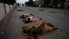 Para pekerja tidur di pinggir jalan pada pagi hari yang panas di awal musim panas di Karachi, Pakistan, Rabu, 29 Mei 2024. (AP Photo/Fareed Khan)