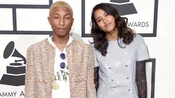 Pharrell Williams dan istrinya, Helen Lasichanh, berpose di karpet merah Grammy Awards 2016 di Los Angeles, Senin (15/2). Rapper 42 tahun itu mengenakan jeans beraksen sobekan dipadukan jaket coklat tak berkerah. (Jason Merritt/Getty Images for NARAS/AFP)