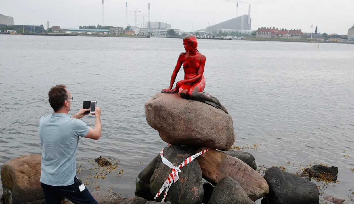 Turis memotret patung putri duyung 'Little Mermaid' yang menjadi korban vandalisme sekelompok aktivis lingkungan di Kopenhagen, Denmark, Selasa (30/5). Patung bersejarah dan jadi ikon itu memerah seolah bersimbah darah. (Jens Dresling/Ritzau Foto via AP)