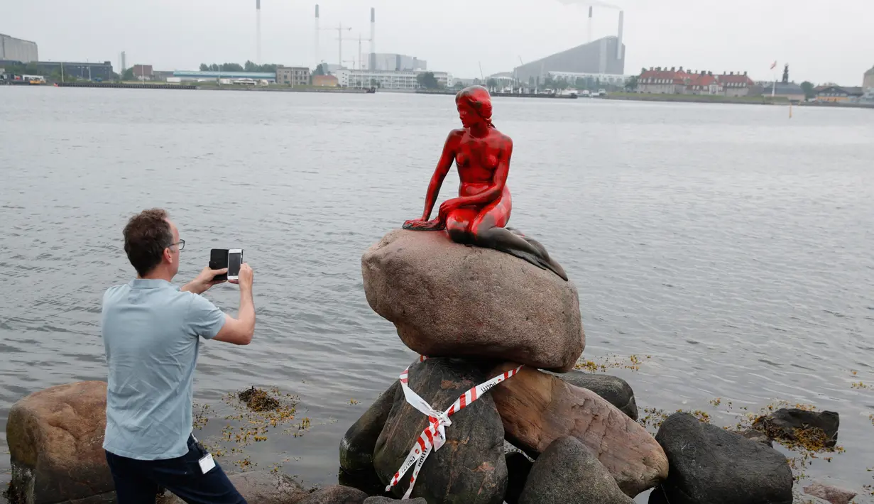Turis memotret patung putri duyung 'Little Mermaid' yang menjadi korban vandalisme sekelompok aktivis lingkungan di Kopenhagen, Denmark, Selasa (30/5). Patung bersejarah dan jadi ikon itu memerah seolah bersimbah darah. (Jens Dresling/Ritzau Foto via AP)