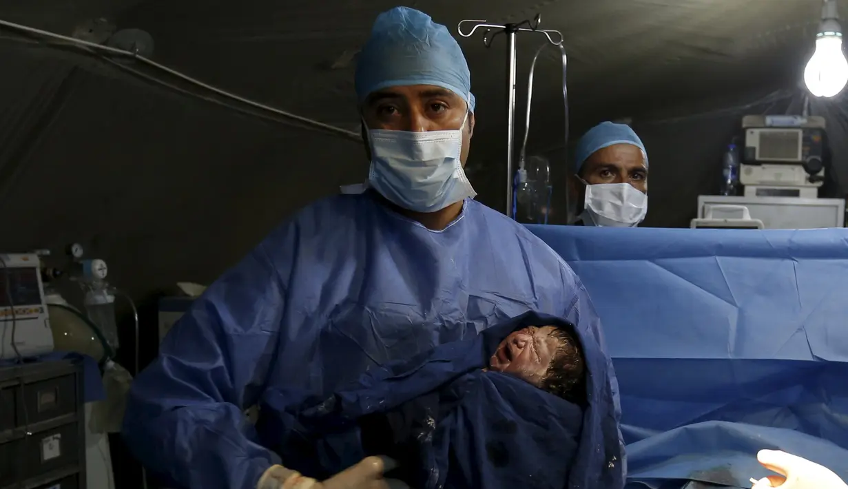 Bayi Siwar digendong dokter asal Maroko usai lahir melalui operasi cesar di rumah sakit kamp pengungsian Al Zaatari, Yordania, 7 Maret 2016. Siwar adalah anak ketiga dari keluarga Daraa asal Suriah yang lahir di kamp pengungsian. (REUTERS/Muhammad Hamed)