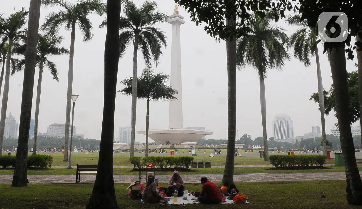 Pengunjung beristirahat sambil menikmati suasana kawasan Monas, Jakarta, Selasa (26/12/2023). (merdeka.com/Imam Buhori)
