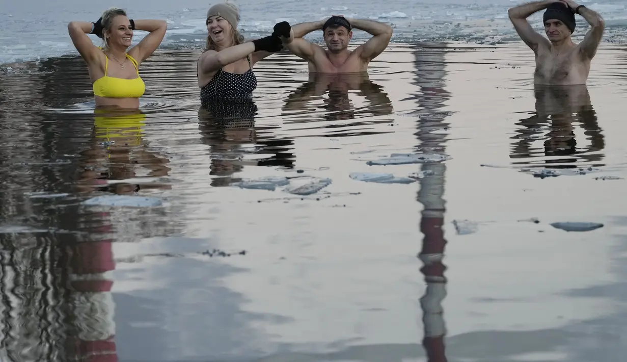 Orang-orang berenang di danau dengan suhu di bawah titik beku di Warsawa, Polandia (26/12/2021). Iklim di Polandia pada musim dingin yang sangat dingin, seringkali di bawah titik beku (0 °C atau 32 °F), dan musim panas yang hangat.  (AP Photo/Czarek Sokolowski)