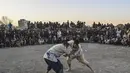 Pria Afghanistan bergulat di latar belakang selama tontonan gulat mingguan yang diadakan di arena darurat di taman Chaman-e-Hozori, di Kota Kabul (12/11/2021). (AFP/Hector Retamal)